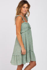 woman wearing a sage green floral smocked maternity dress with ruffle straps and a tiered skirt