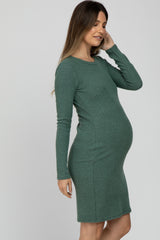 woman wearing a long sleeve green maternity dress showcasing her baby bump