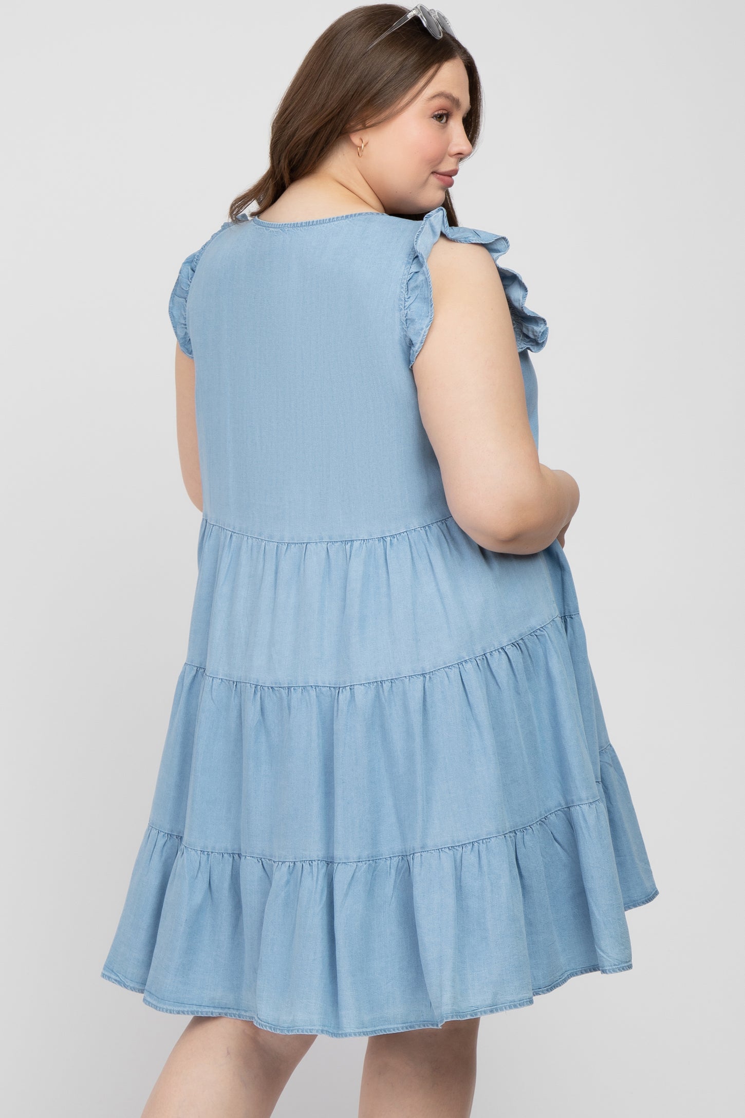 woman wearing a light blue tiered maternity dress with ruffled sleeves, showcasing a relaxed fit and rounded hem