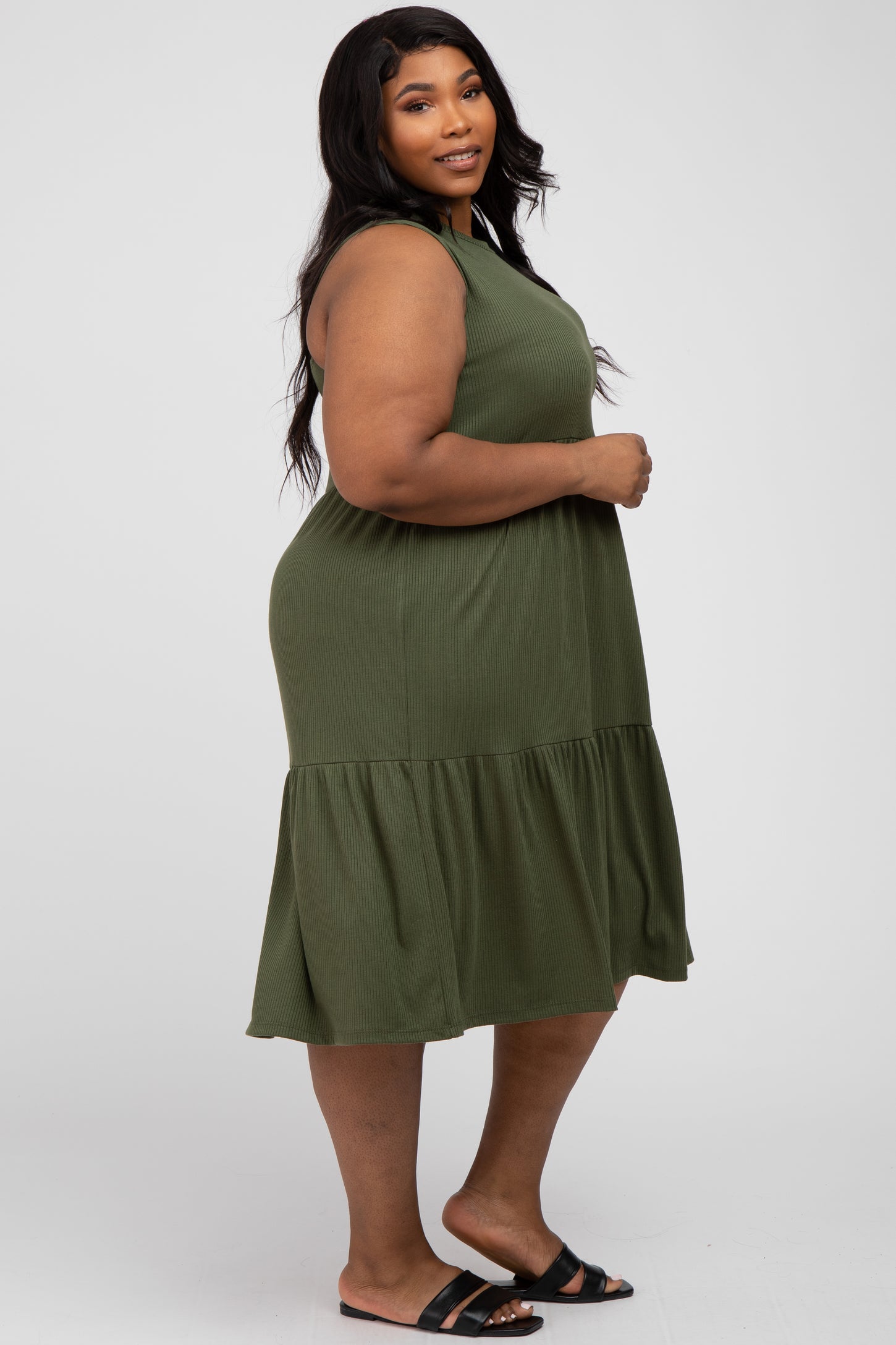 plus size woman wearing an olive green ribbed knit tiered sleeveless midi dress and black sandals
