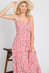 smiling woman in pink floral maxi dress and straw hat posing against a white background