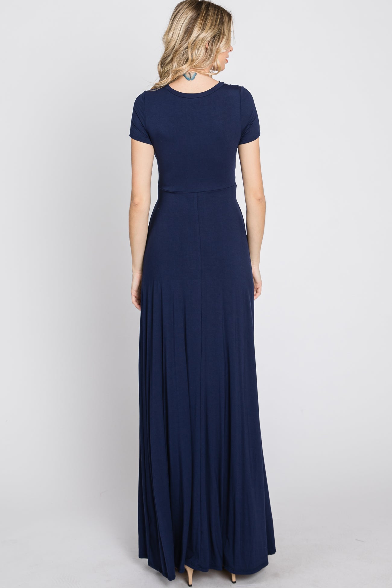 woman wearing a navy blue short sleeve maxi dress, showing the back view with a flowing skirt
