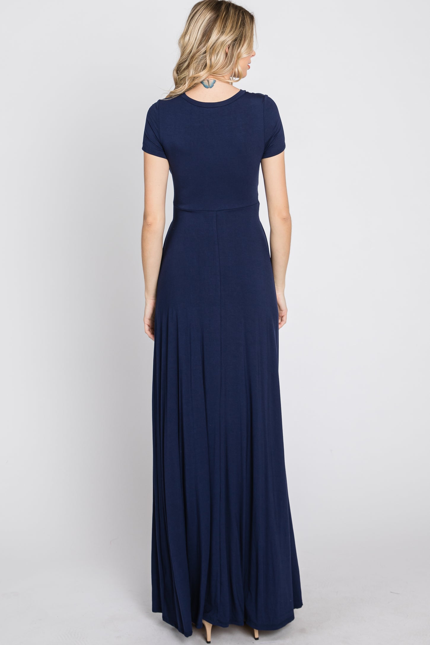 woman wearing a navy blue short sleeve maxi dress, showing the back view with a flowing skirt
