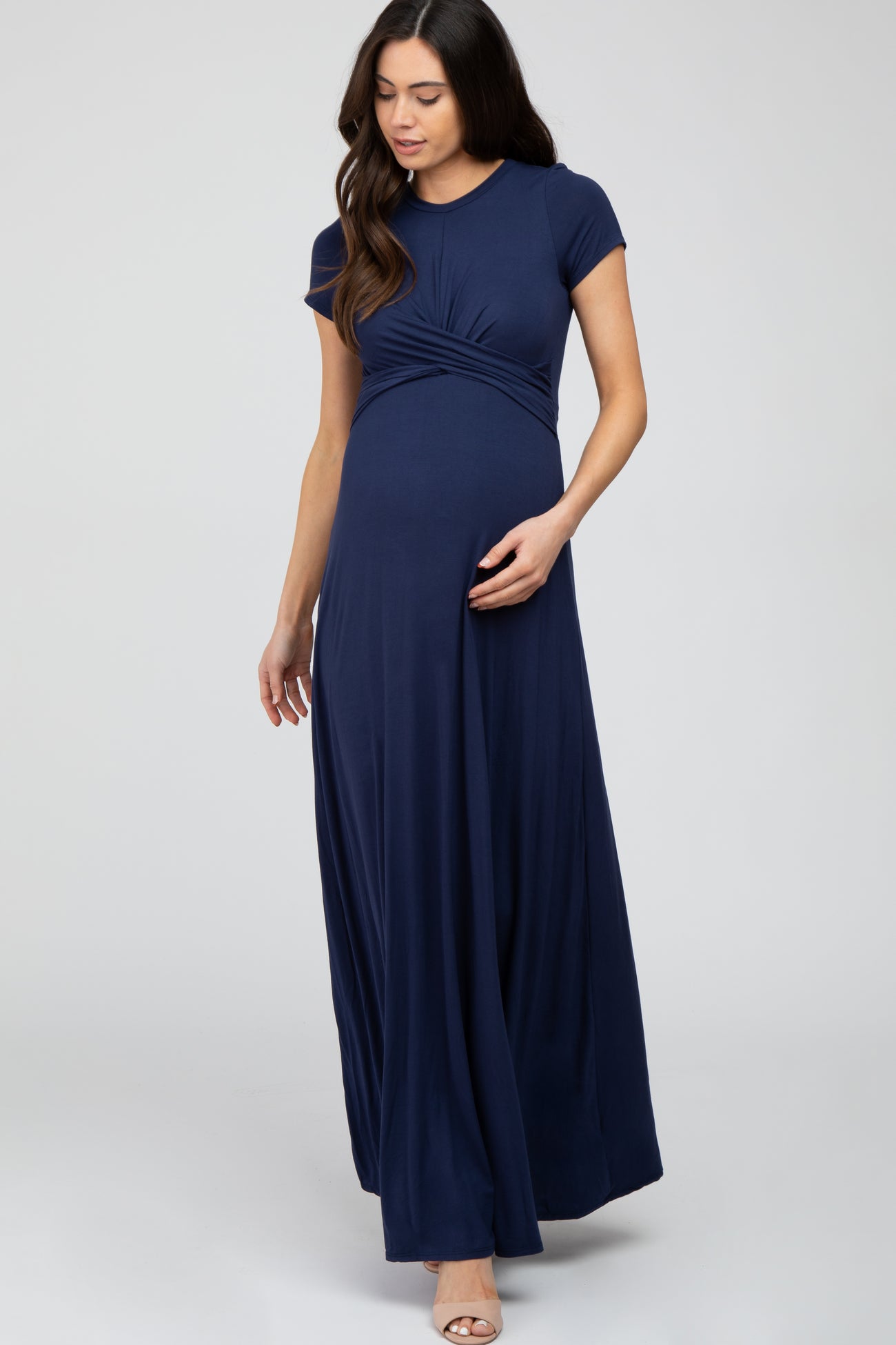 woman wearing a navy blue short sleeve maternity maxi dress and cradling her baby bump