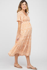 woman wearing a floral orange maternity dress with a tiered skirt and a visible baby bump