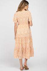 woman wearing a short sleeve orange floral maternity dress with a tiered skirt, showcasing a baby bump from the back