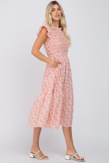 woman wearing a blush pink midi dress with ruffle sleeves and floral print, featuring pockets and a fitted bodice