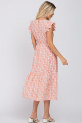 woman wearing a pink tropical print midi dress with ruffle sleeves and a smocked waist, viewed from the back