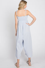Woman from behind wearing a light blue smocked jumpsuit with tie straps and wide legs