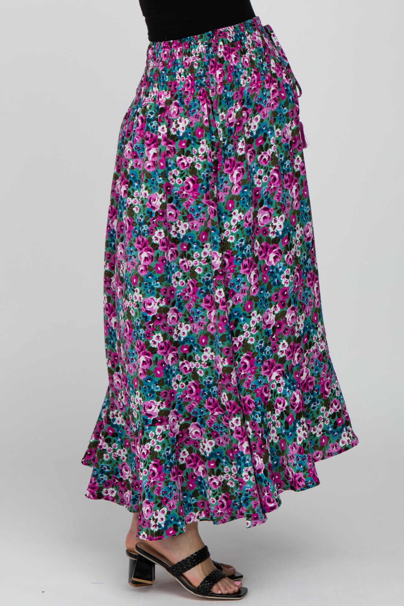 woman wearing a long floral print maxi skirt with pink and blue flowers and black strappy sandals