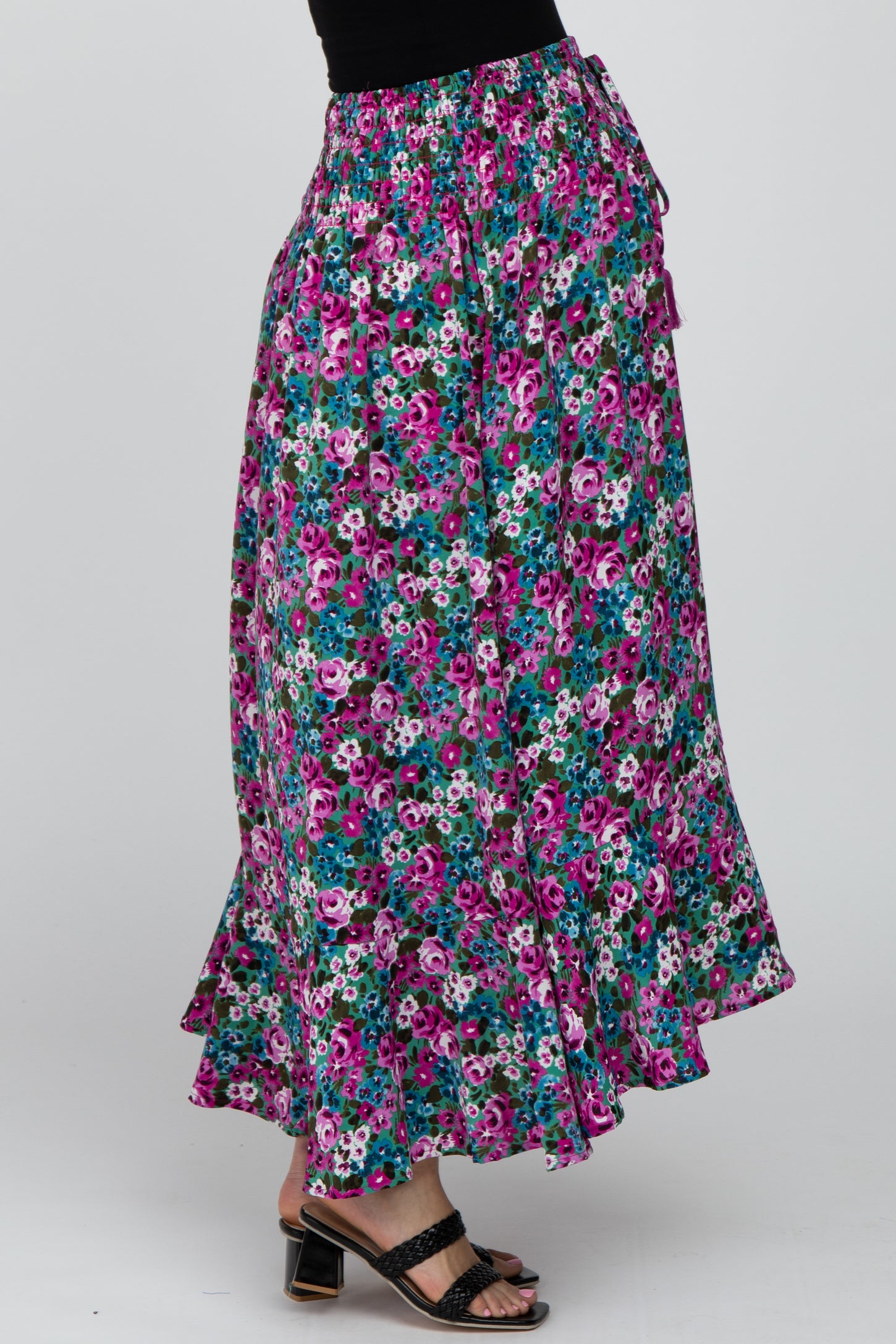 woman wearing a long floral print maxi skirt with pink and blue flowers and black strappy sandals