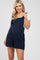 Pregnant woman wearing navy blue maternity romper over a white t-shirt against a white background