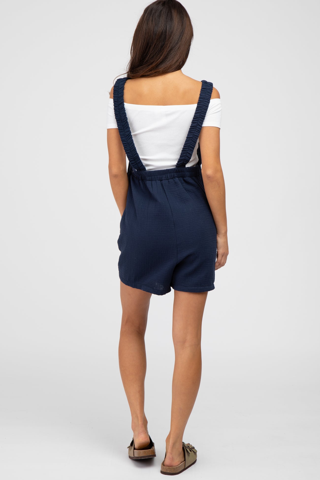 woman wearing a navy ribbed short romper with adjustable straps and a relaxed fit, seen from the back