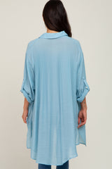 woman wearing a light blue oversized button-up shirt with rolled sleeves and a flowy back design