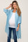 woman wearing a light blue maternity button-up shirt over a white tank top and showing her baby bump with jeans