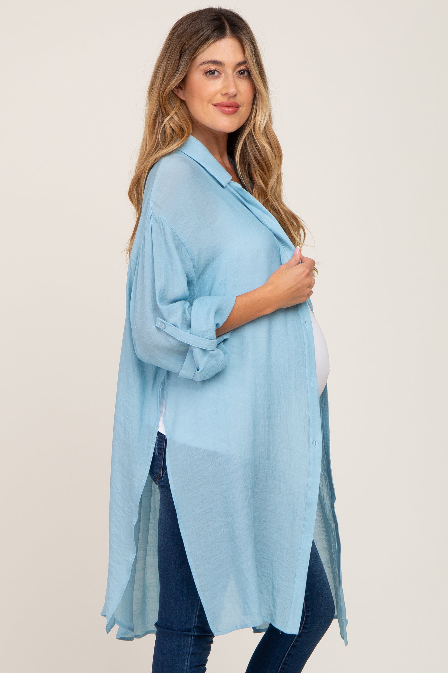 woman wearing a light blue maternity wrap shirt with rolled sleeves and a visible baby bump