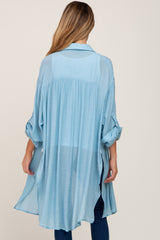 woman wearing a light blue maternity tunic with rolled sleeves and a flowy back design