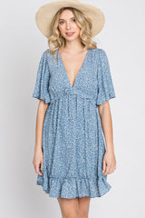 woman wearing a blue floral print mini dress with a v-neckline and a straw sun hat