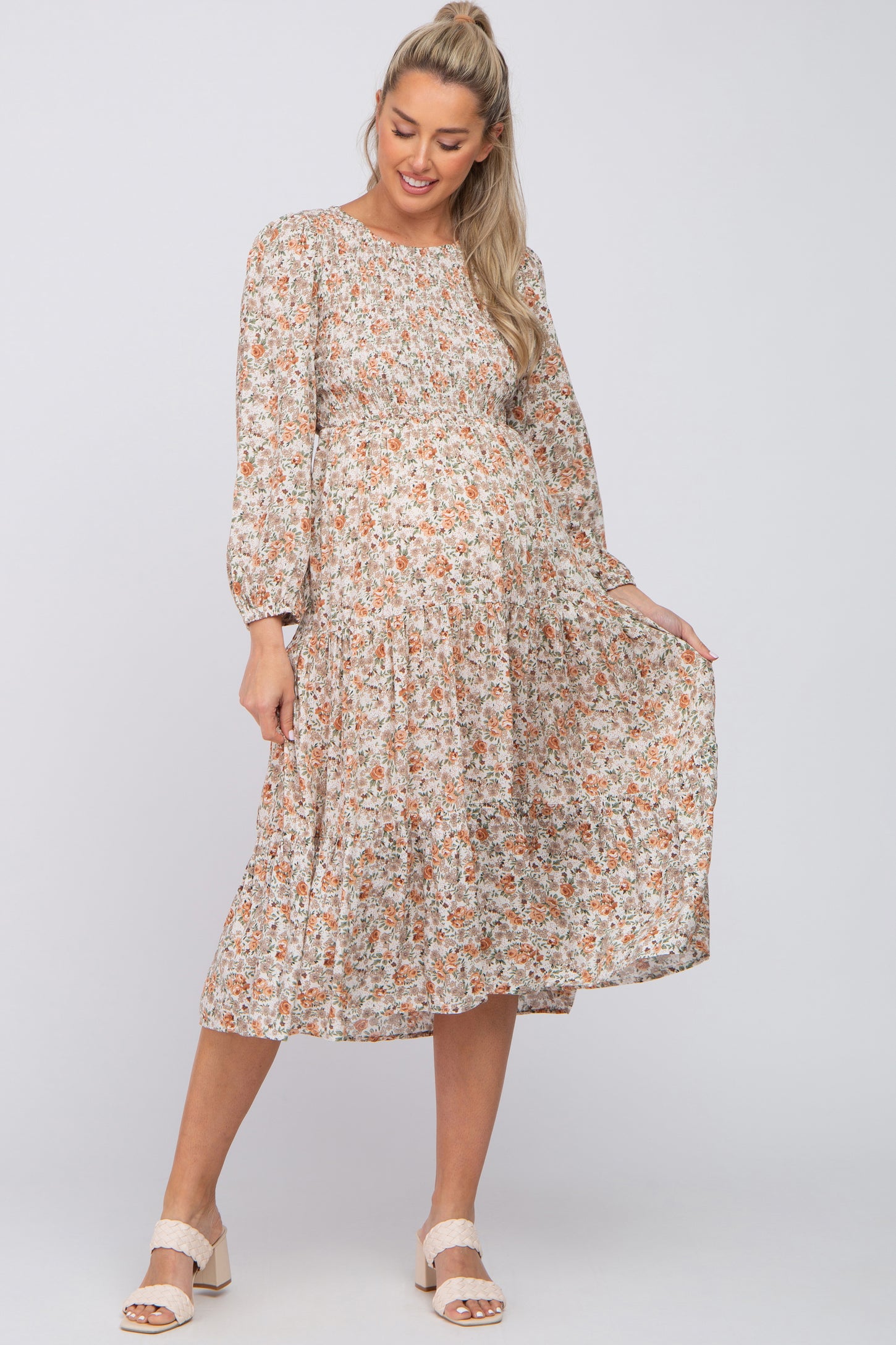 pregnant woman wearing a long sleeve floral tiered maternity midi dress with cream block heel sandals