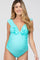 smiling pregnant woman wearing a light blue ruffled maternity one-piece swimsuit