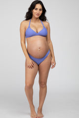 woman wearing a purple maternity bikini top and bottom, showcasing her baby bump