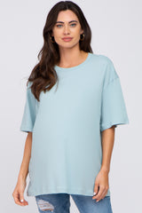 woman wearing a light blue oversized maternity t-shirt and distressed jeans, showing a baby bump
