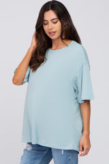 woman wearing a light blue oversized maternity t-shirt with short sleeves and styled hair, baby bump visible