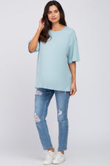 woman wearing a light blue oversized maternity top and distressed skinny jeans, casual outfit with white sneakers