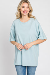 woman wearing a light blue oversized t-shirt with short sleeves and smiling