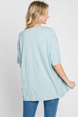 back view of a woman wearing an oversized light blue t-shirt and blue jeans against a white background