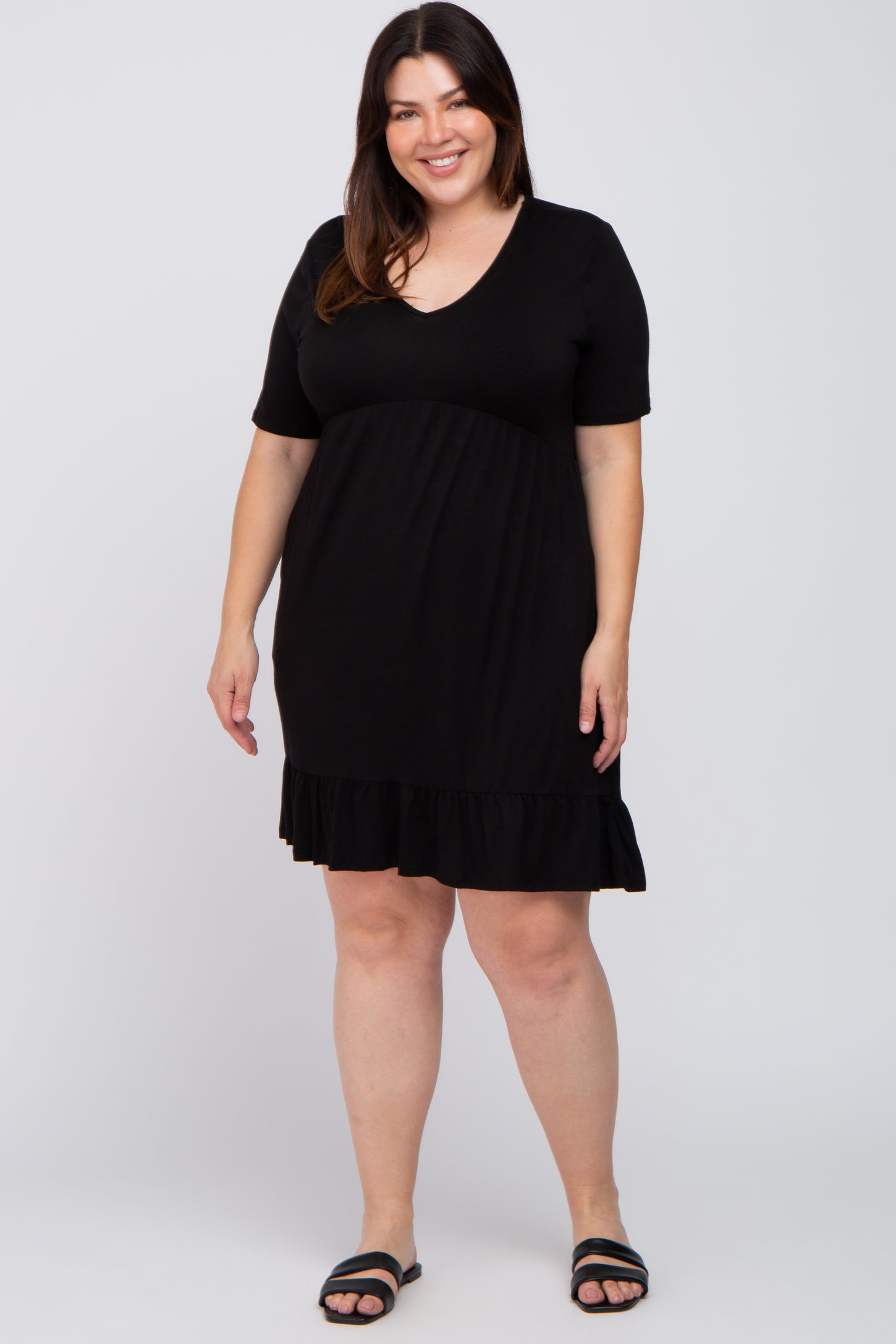 woman wearing a black short sleeve plus size dress with a ruffled hem and v-neckline