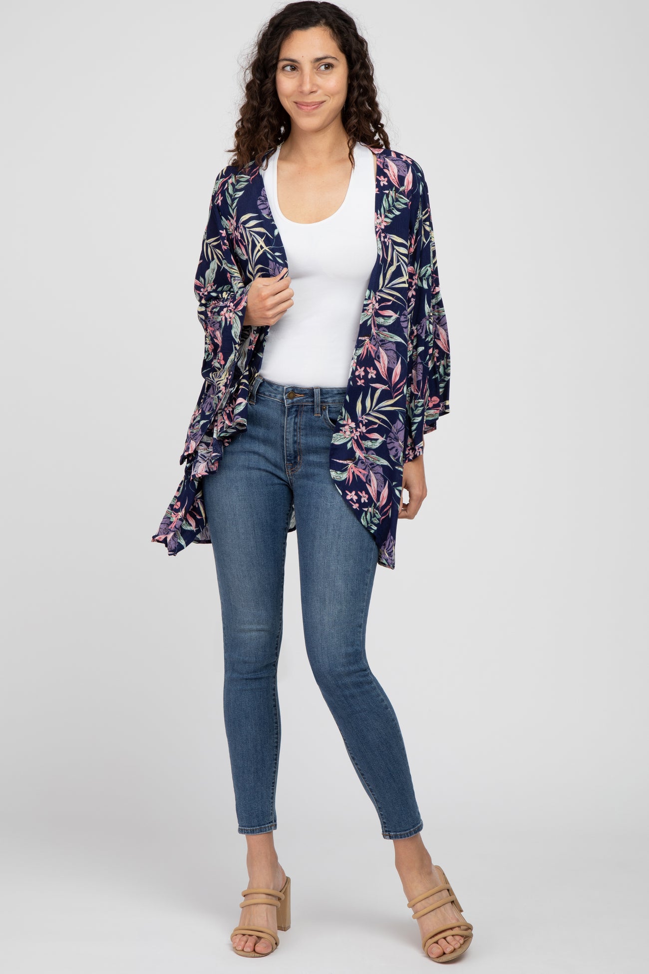woman wearing a floral navy kimono over a white tank top and high-waisted jeans with beige block-heel sandals