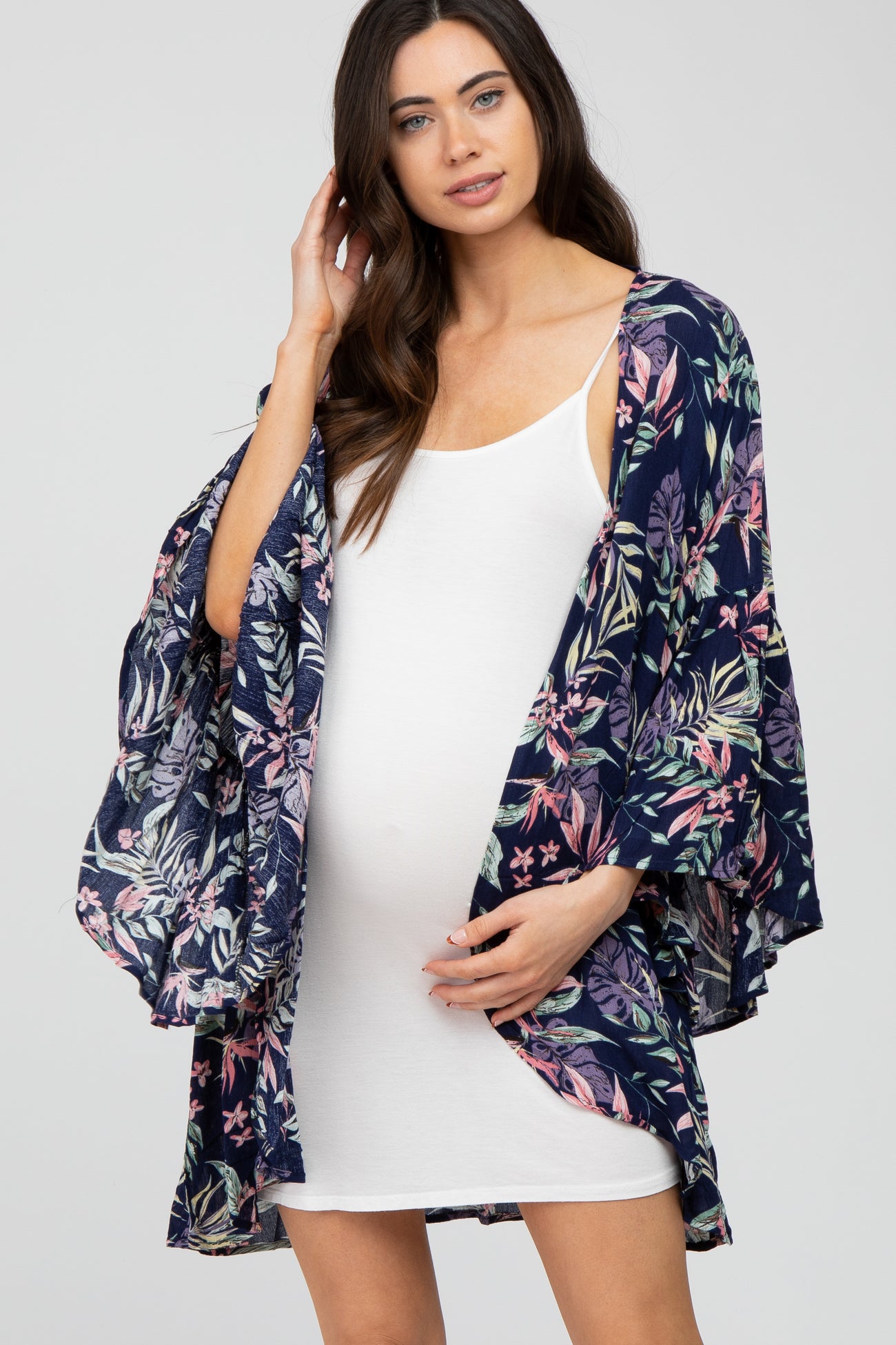 woman wearing a navy floral maternity kimono over a white tank dress with a visible baby bump