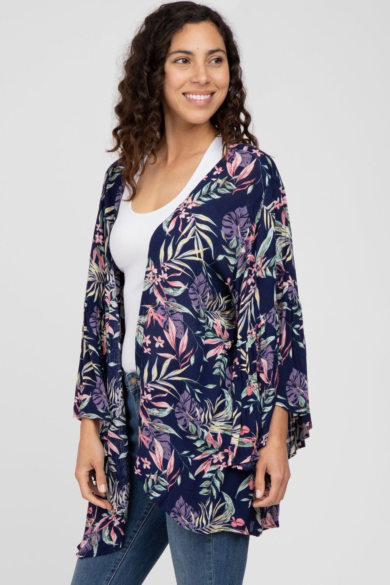 woman wearing a navy floral kimono cardigan over a white top and blue jeans