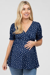 Pregnant woman wearing a navy blue floral maternity top with short puff sleeves and a wrap neckline