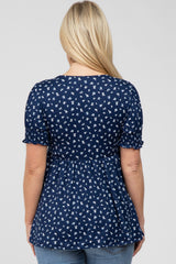 Back view of a woman wearing a navy blue floral print babydoll top with short ruffled sleeves
