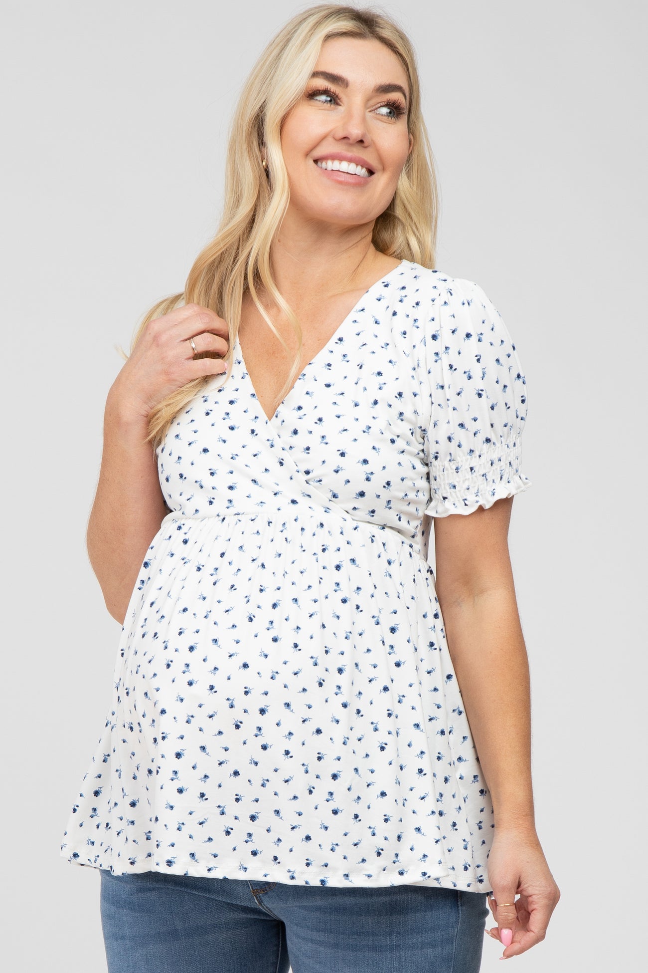 woman wearing a white maternity top with blue floral print and puff sleeves, showing her baby bump