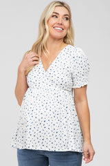 woman wearing a white maternity top with blue floral print and puff sleeves, showing her baby bump