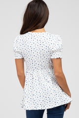 woman wearing a white short sleeve blouse with navy floral print and smocked details, shown from the back