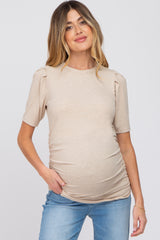 woman wearing a beige short sleeve maternity top with puff shoulders and a visible baby bump