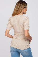 woman wearing a beige short sleeve maternity top with ruffle details on the shoulders and fitted silhouette