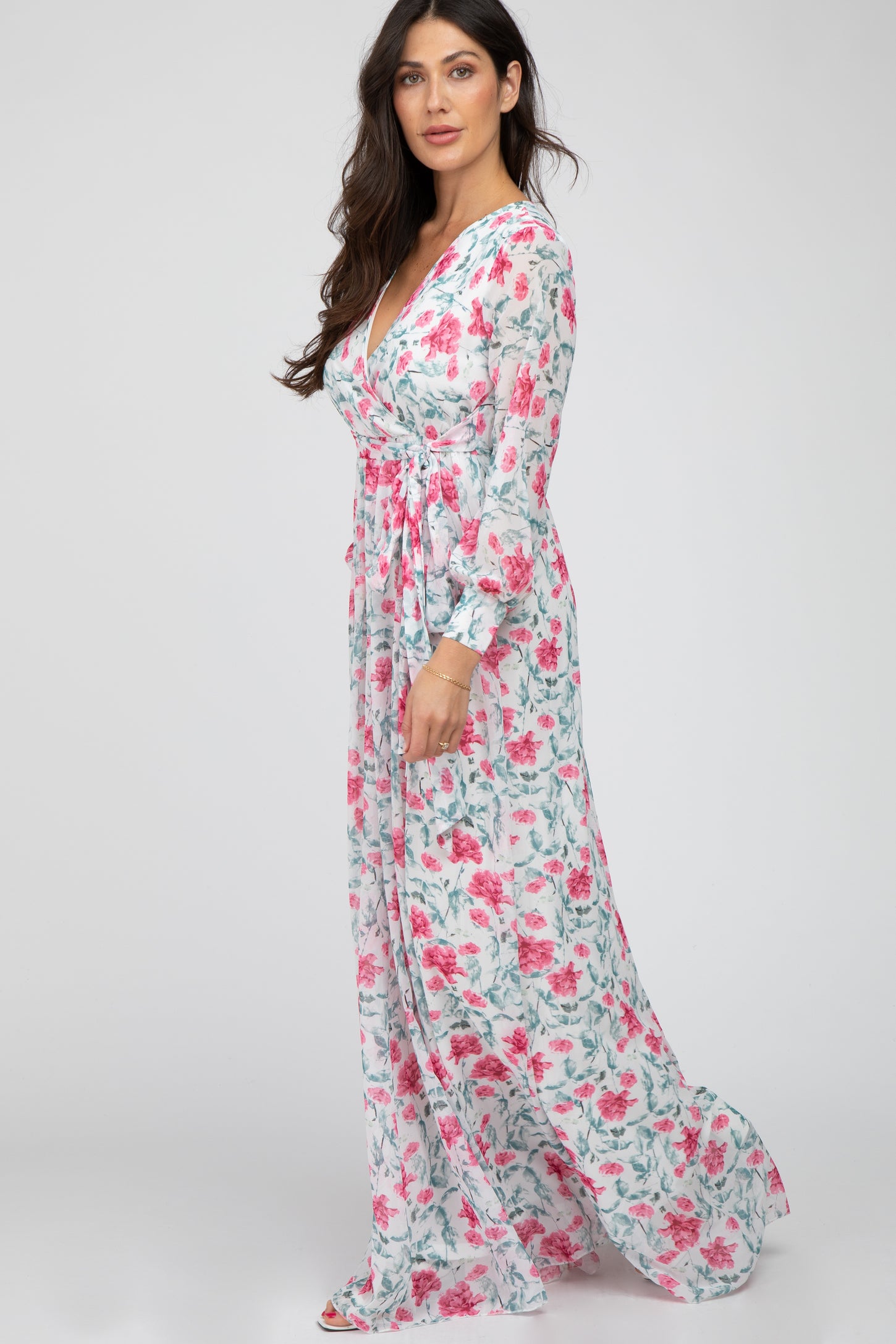 woman wearing a long sleeve white floral maxi dress with pink roses and a wrap v-neckline