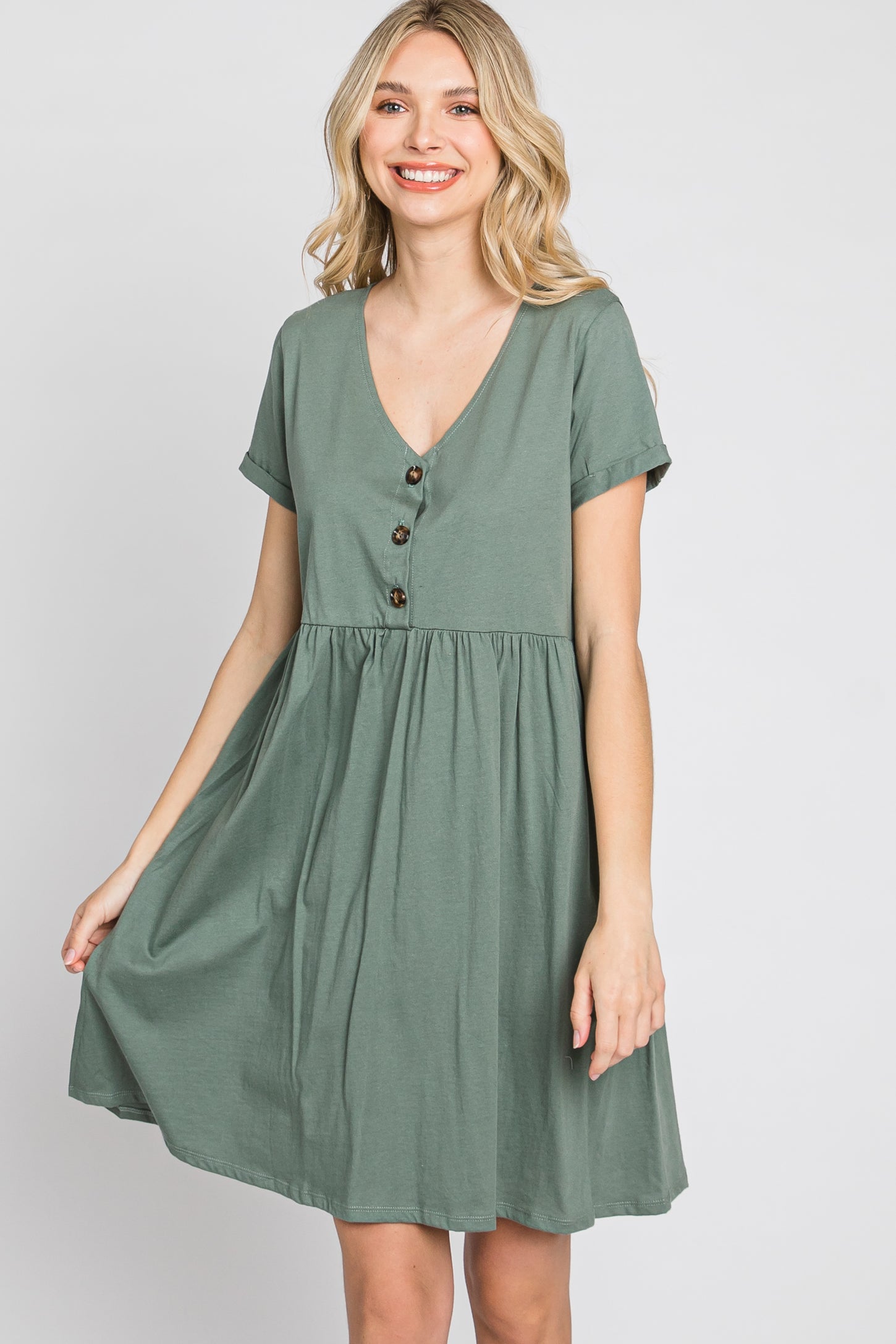 smiling woman wearing a short sleeve sage green v-neck babydoll dress with front buttons