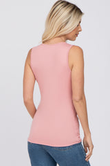 back view of a woman wearing a fitted sleeveless pink tank top and blue jeans