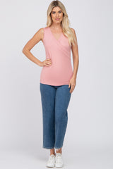 woman wearing a light pink sleeveless wrap top and high-waisted blue jeans with white sneakers