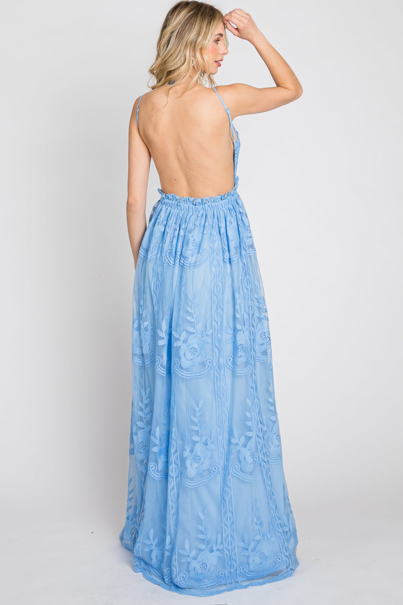 Woman wearing a light blue backless maxi dress with floral lace embroidery and thin straps