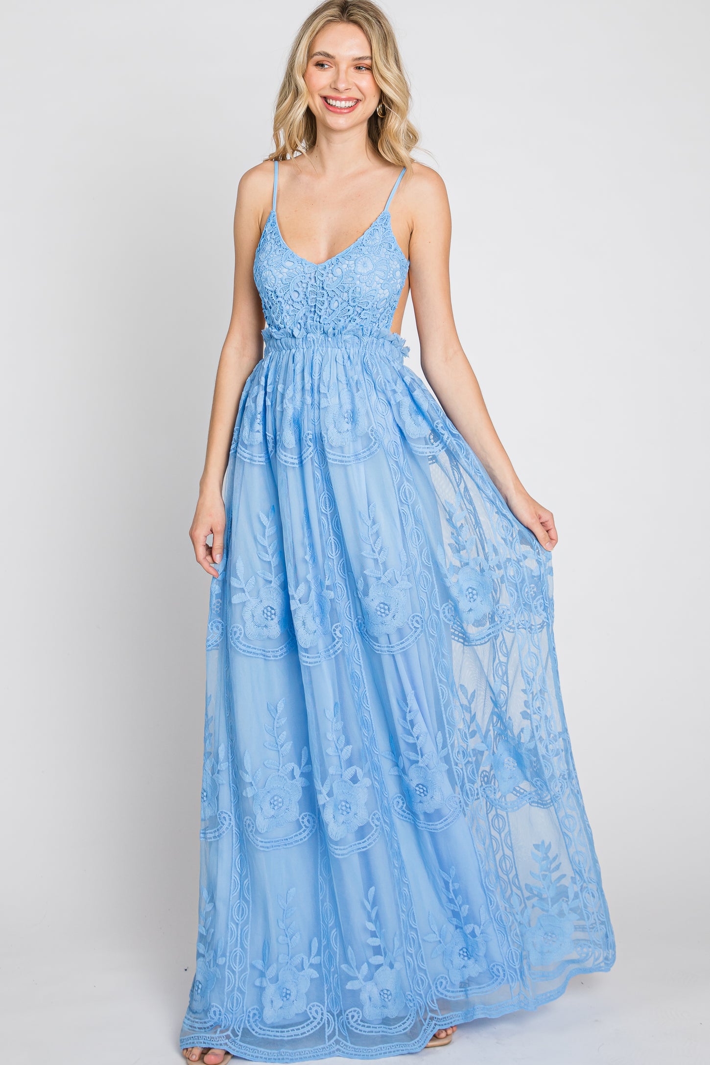 smiling woman wearing a light blue lace maxi dress with spaghetti straps and floral embroidery
