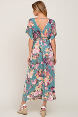 Woman from behind wearing a teal floral maxi dress with a v-back and white wedge sandals