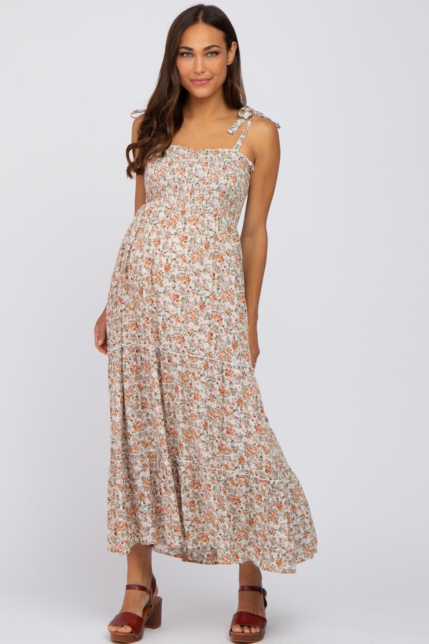 woman wearing a floral maxi maternity dress with shoulder ties and a visible baby bump