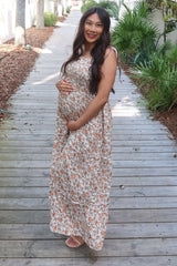 woman wearing a floral print maternity maxi dress and holding her baby bump while walking on a wooden pathway